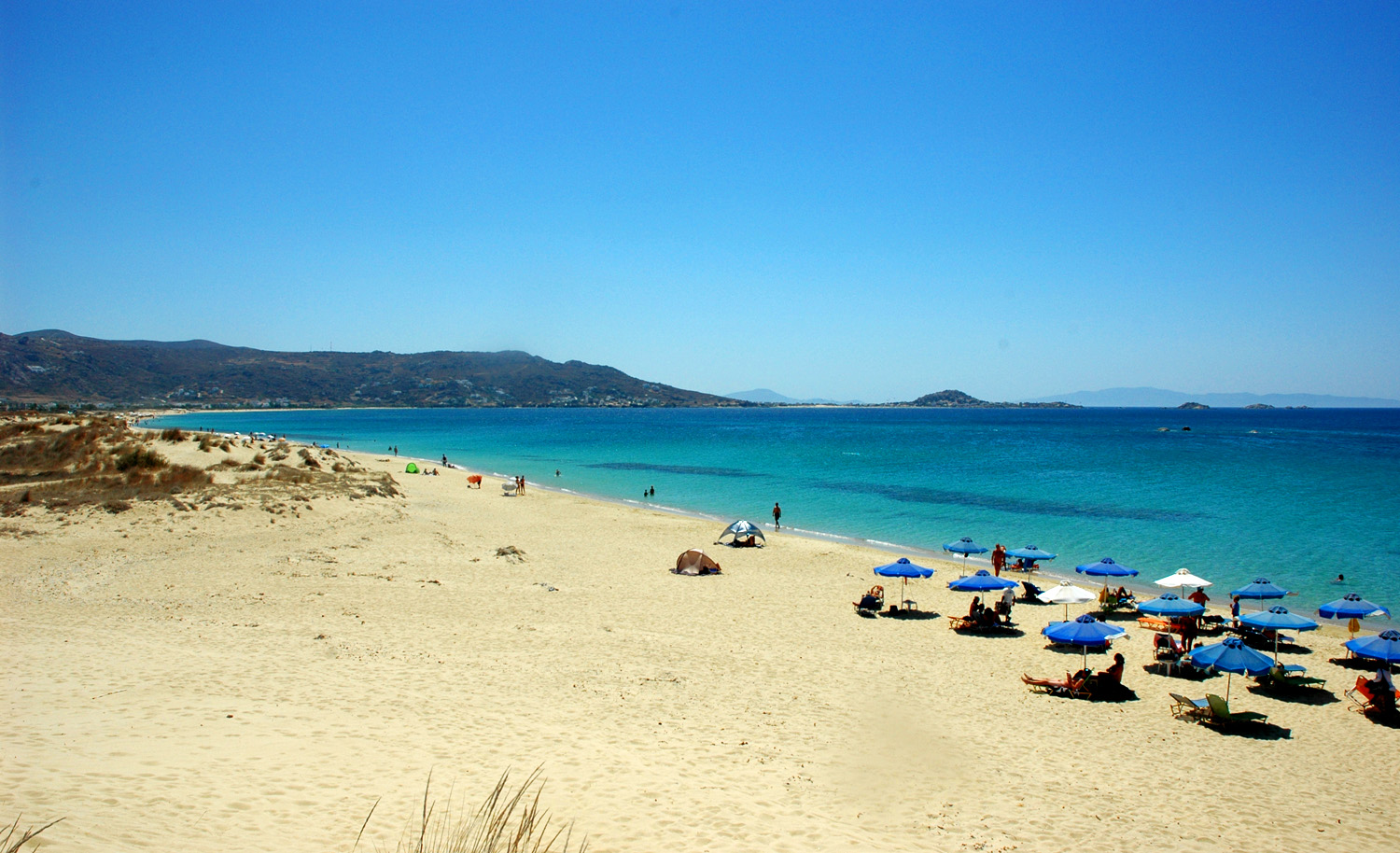 Plaka Beach in Naxos, featuring a sandy shoreline with calm water conditions