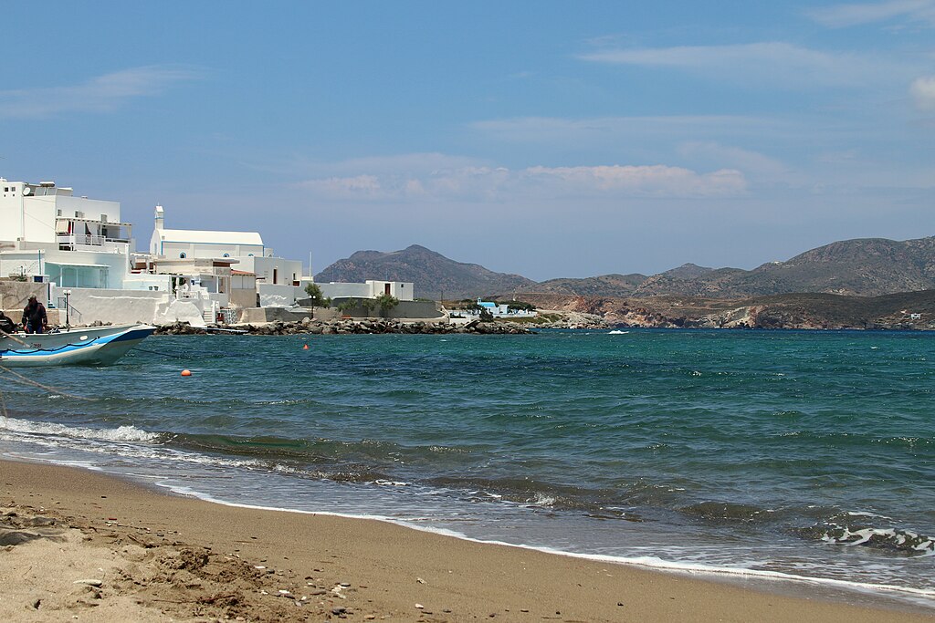 Pollonia Beach in Milos, featuring a sandy shoreline with calm water conditions